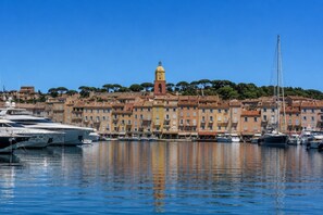 A marina with boats docked, a prominent clock tower, and buildings with uniform architecture.