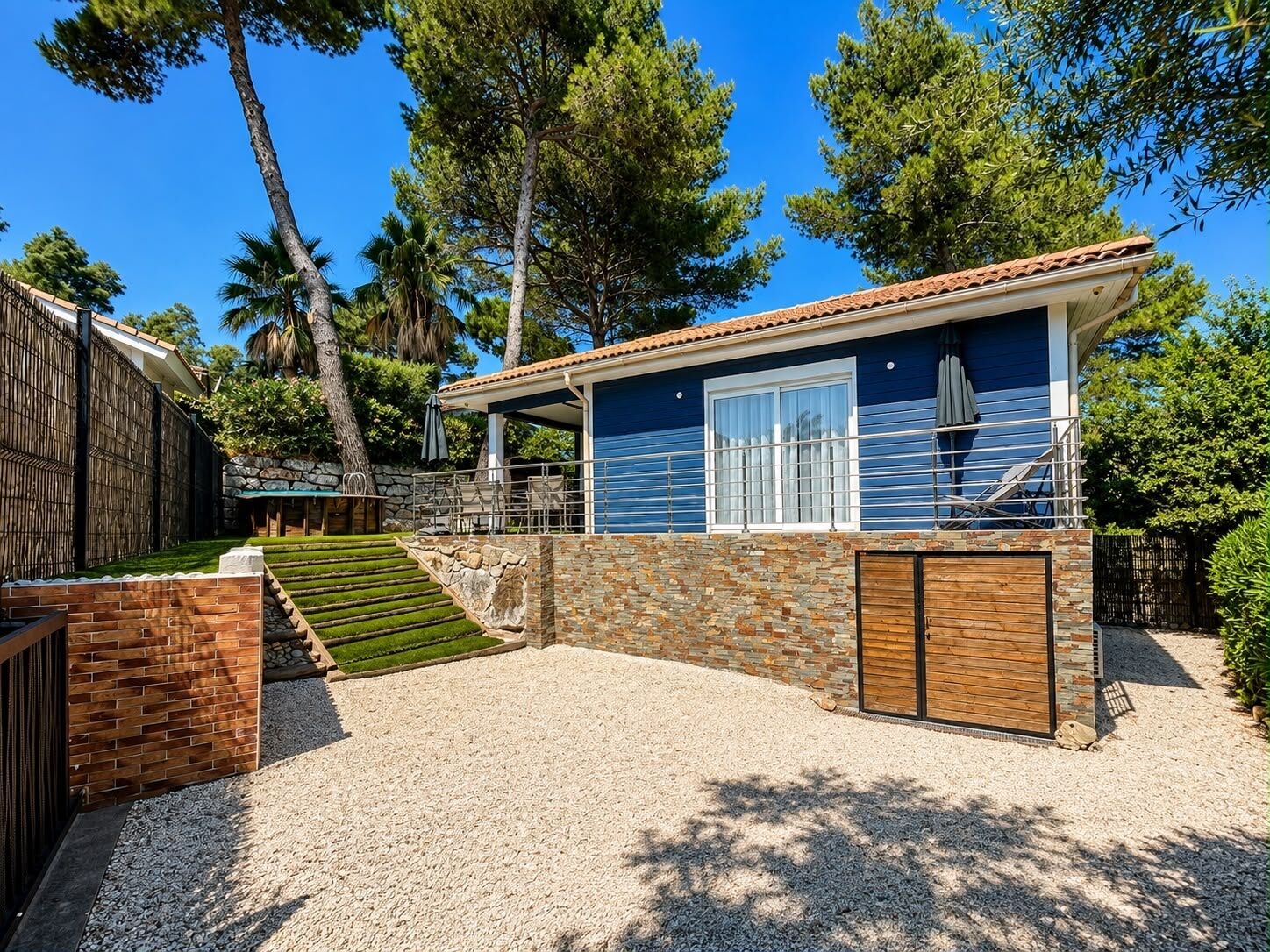 A two-story building with a stone facade, a wooden deck, and a clear blue sky.