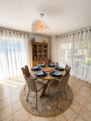 A dining room with a round table set for six, surrounded by chairs, a patterned rug, and a wooden cabinet with glass doors.