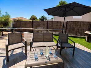 An outdoor patio with a table, chairs, and an umbrella.