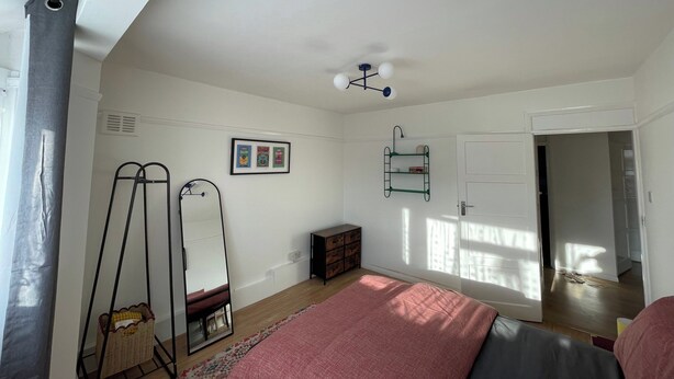 A bedroom with a bed, a mirror, a dresser, a shelf, and a door. - Romford Retreat - Modern 2 Bedroom Apartment (Romford)