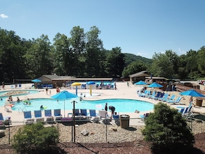 Un espace piscine comprenant plusieurs piscines, des chaises longues et des parasols.
