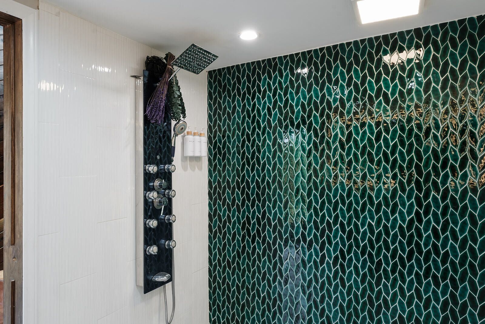 Uma casa de banho com chuveiro, porta-toalhas fixado na parede e painel decorativo.