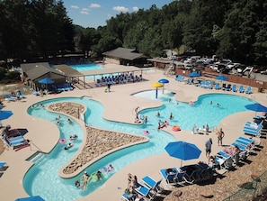 Un área de piscina con múltiples carriles, sillas de descanso y sombrillas.