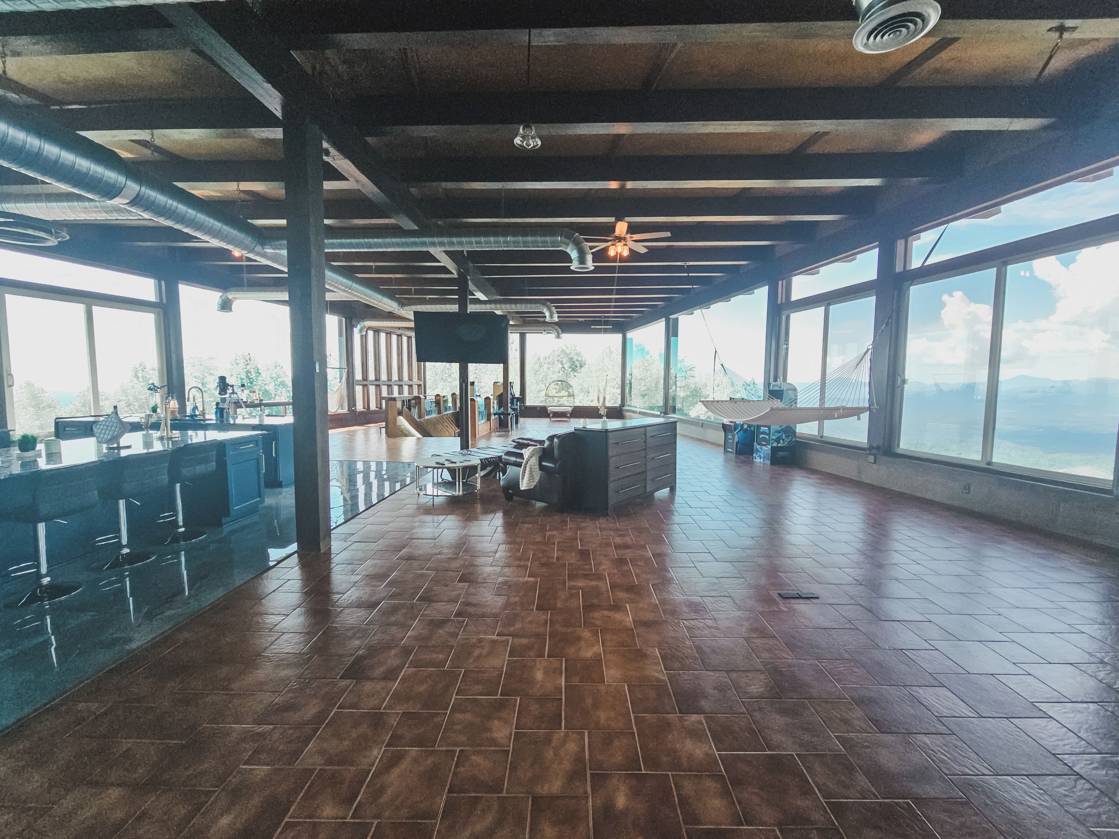 Un amplio espacio interior con barra, asientos y ventanas grandes que ofrecen vistas.