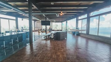 Un amplio espacio interior con barra, asientos y ventanas grandes que ofrecen vistas.