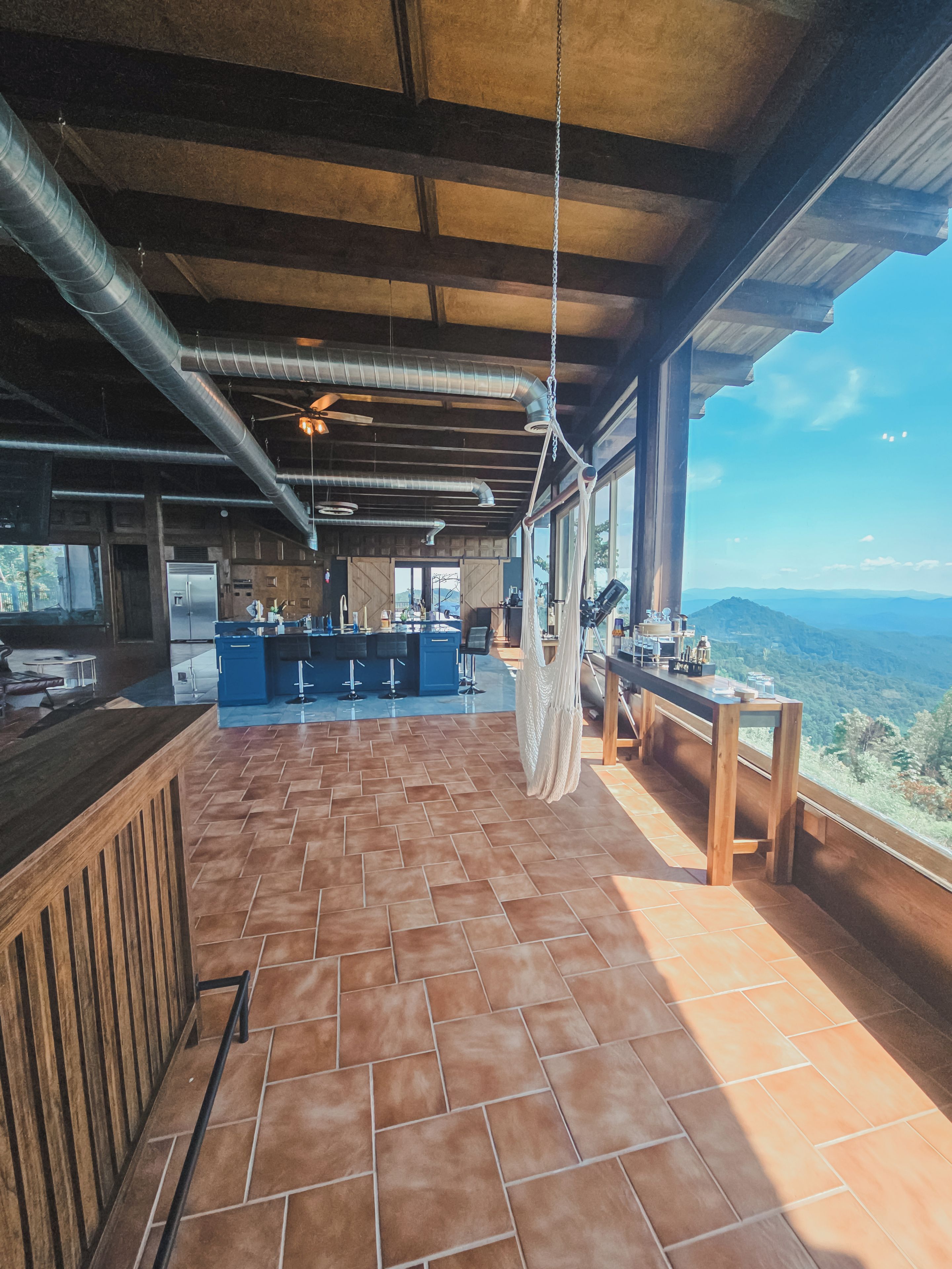 A spacious terrace with a bar area, a hanging hammock, and a view of the mountains.