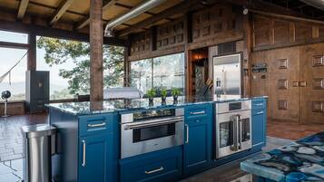 A modern kitchen with a central island, stainless steel appliances, and a view of the outdoors.