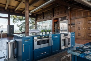 A modern kitchen with a central island, stainless steel appliances, and a view of the outdoors.