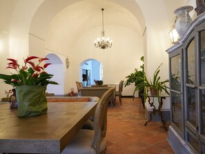 A dining area with a wooden table, chairs, and a chandelier. There are potted plants on the table and a cabinet with glass doors. - Luxury Estate with Private Pool and Panoramic Sea Views (Sorrento)