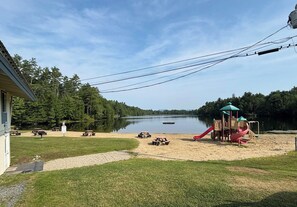 A lakeside property with a playground, picnic tables, and a building. - Serene 4-bedroom house in the beautiful White Mountains. (Haverhill)