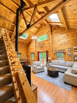 A log cabin interior with a staircase, wooden walls, a sofa, and a dining area.