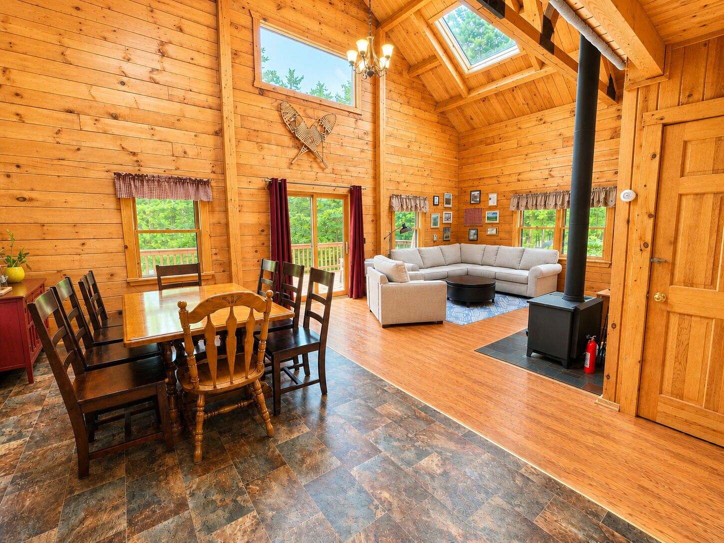 A wooden interior with a dining table, chairs, a sofa, and a fireplace.