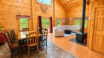 A wooden interior with a dining table, chairs, a sofa, and a fireplace.
