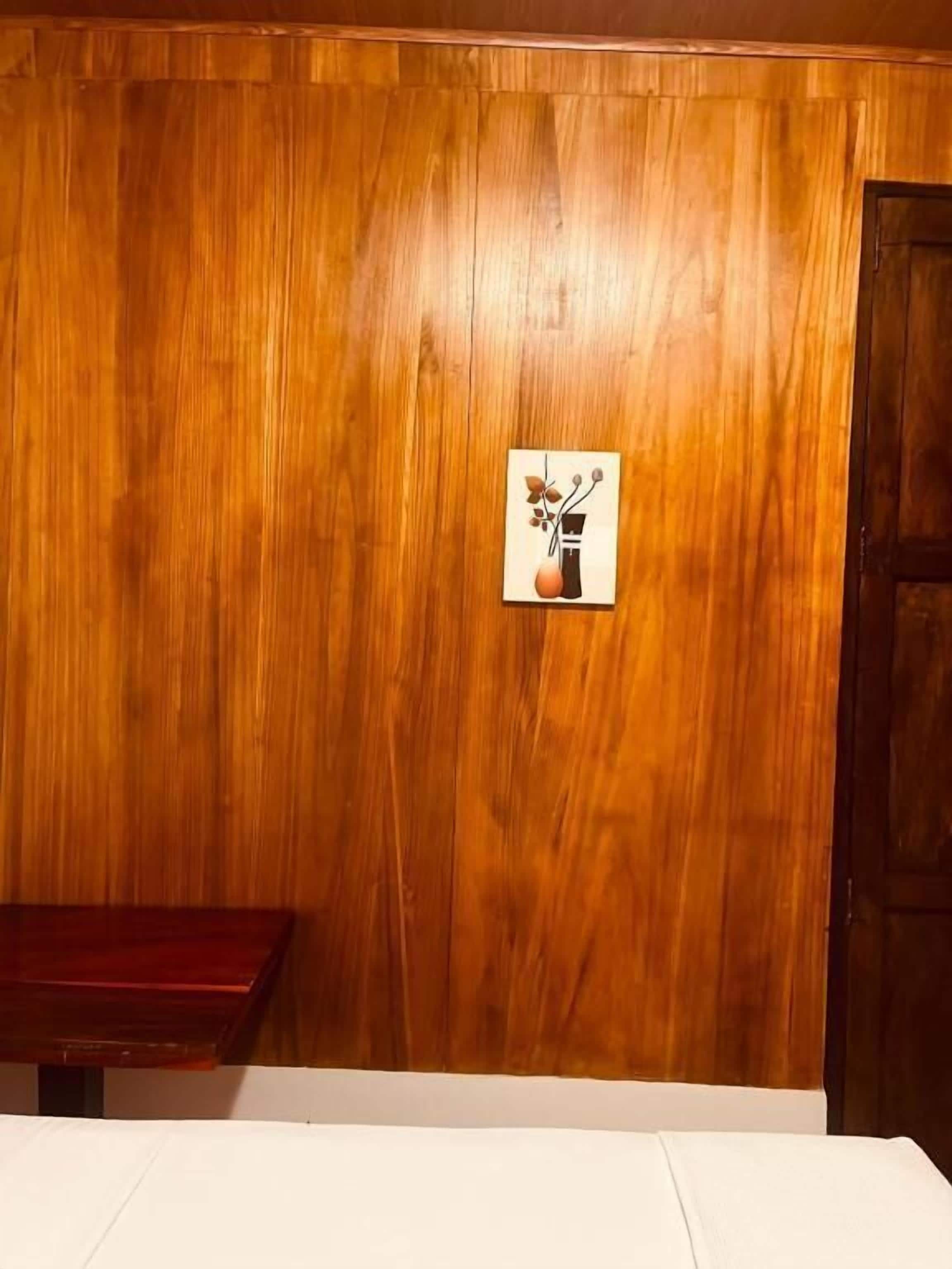 Una habitación con pared de madera, una mesita y una puerta.