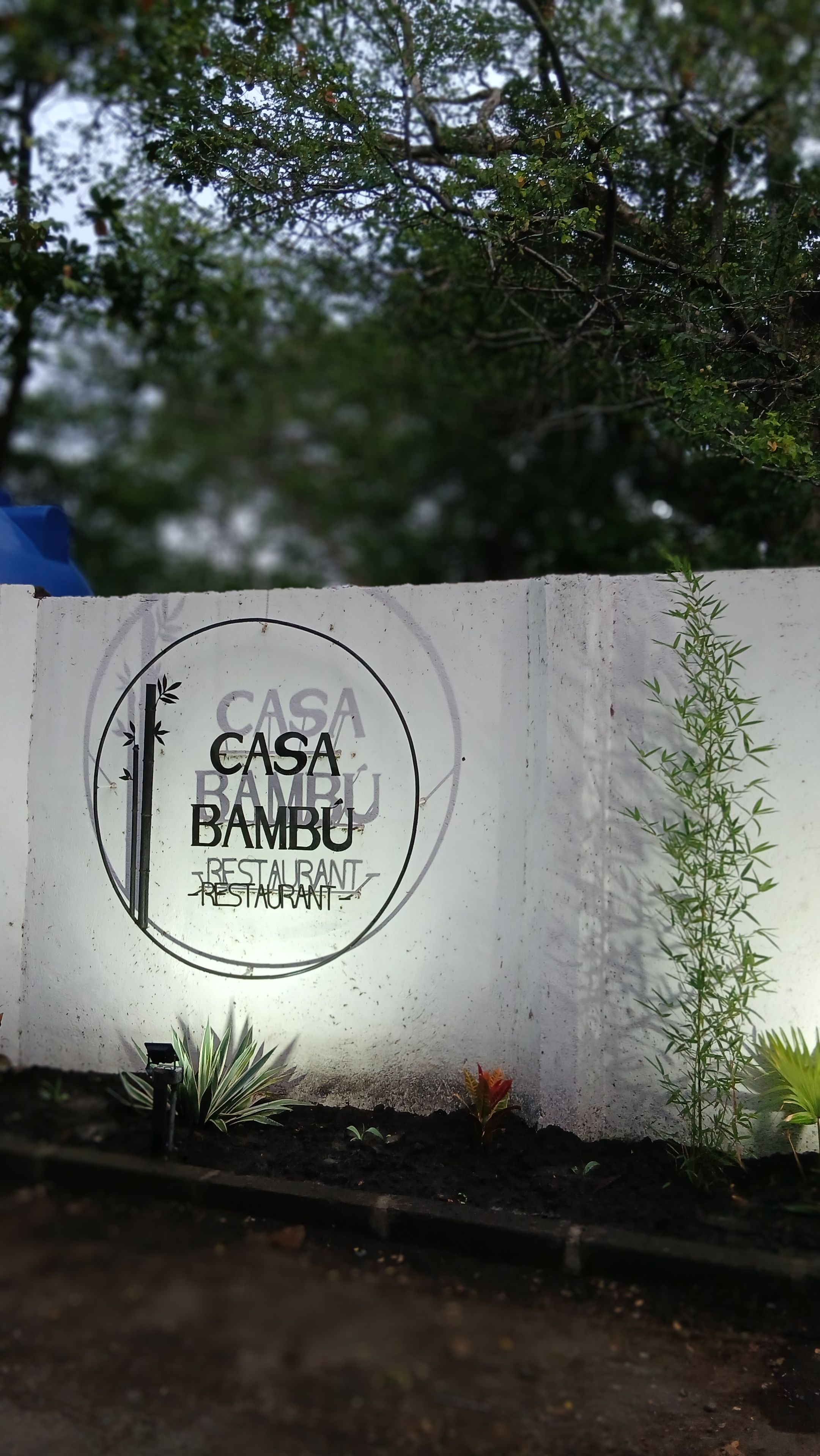 Una pared con un letrero circular que dice 'CASA BAMBU RESTAURANT'.
