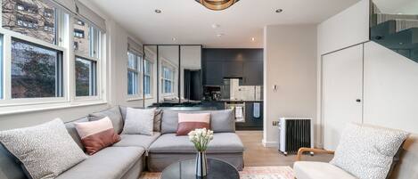 A modern living room with a sectional sofa, a coffee table, and a dining area in the background.