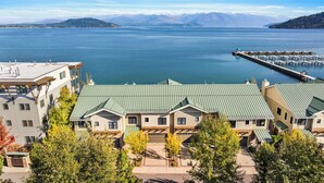 A lakeside hotel with a dock and boats, surrounded by mountains and trees. - Waterfront Townhouse, Private Hot Tub, Boat Slip (Sandpoint)