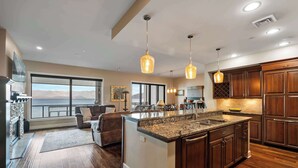 A modern kitchen with a large island, wooden cabinets, and pendant lighting. - Waterfront Townhouse, Private Hot Tub, Boat Slip (Sandpoint)