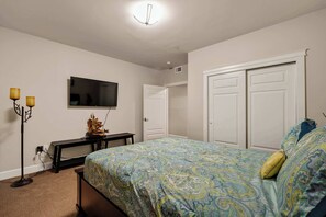 Un dormitorio con cama, televisor, escritorio y armario.
