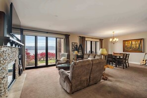 Amplia sala de estar con un ventanal, chimenea, comedor y vistas al exterior.