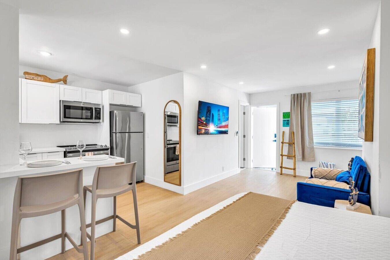 A modern kitchen with white cabinets, stainless steel appliances, and a dining area with two chairs.
