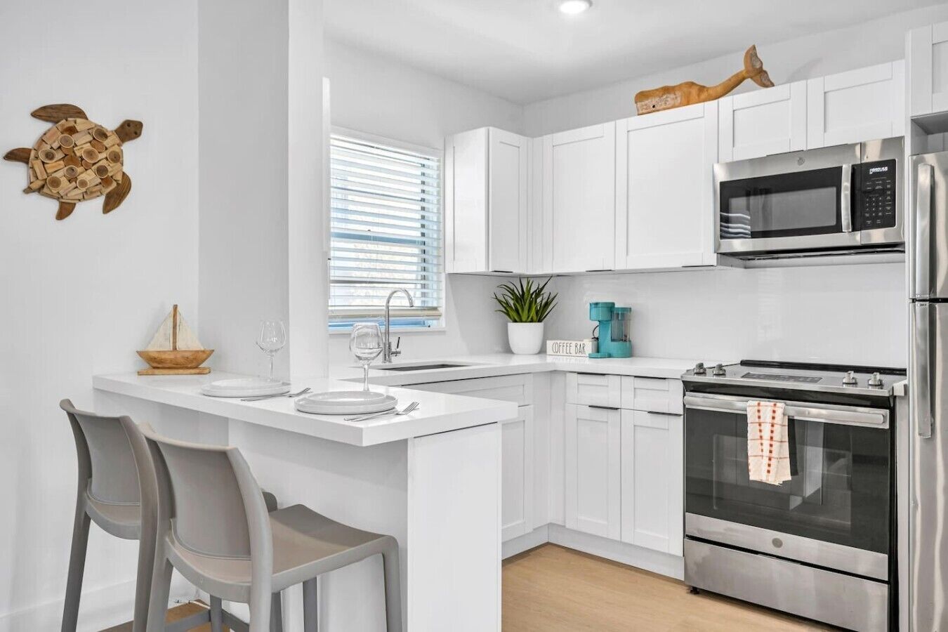 A modern kitchen with white cabinetry, a built-in oven, a microwave, and a coffee maker.