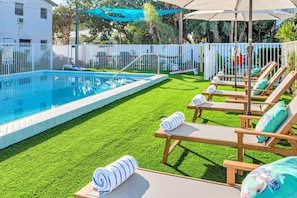 Zona de piscina amb piscina, gandules i gespa.