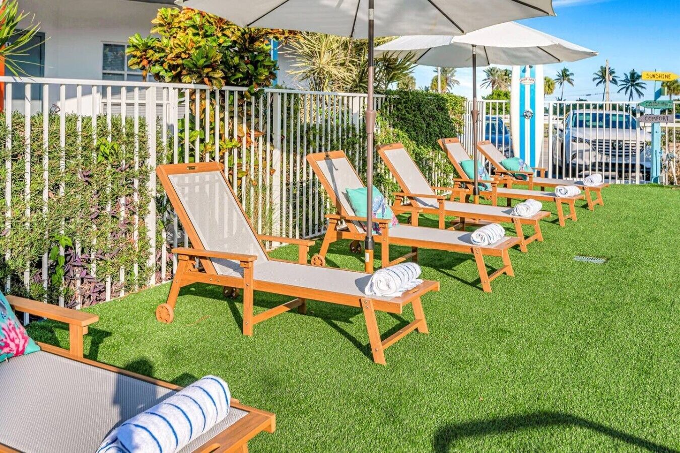 Une rangée de chaises longues avec des serviettes, une clôture blanche et une piscine en arrière-plan.