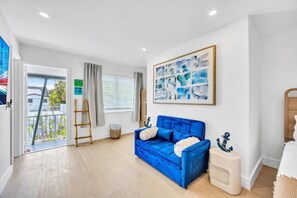 Un saló modern amb un sofà blau, un quadre i una escala de fusta.