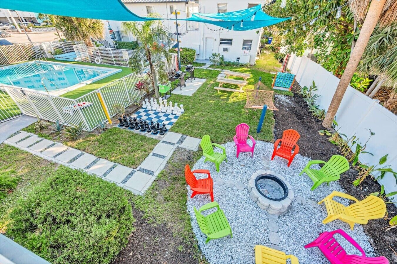 Un jardin avec une piscine, un foyer extérieur et des fauteuils Adirondack aux couleurs vives.