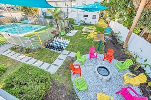 Um quintal com piscina, lareira e cadeiras Adirondack coloridas.
