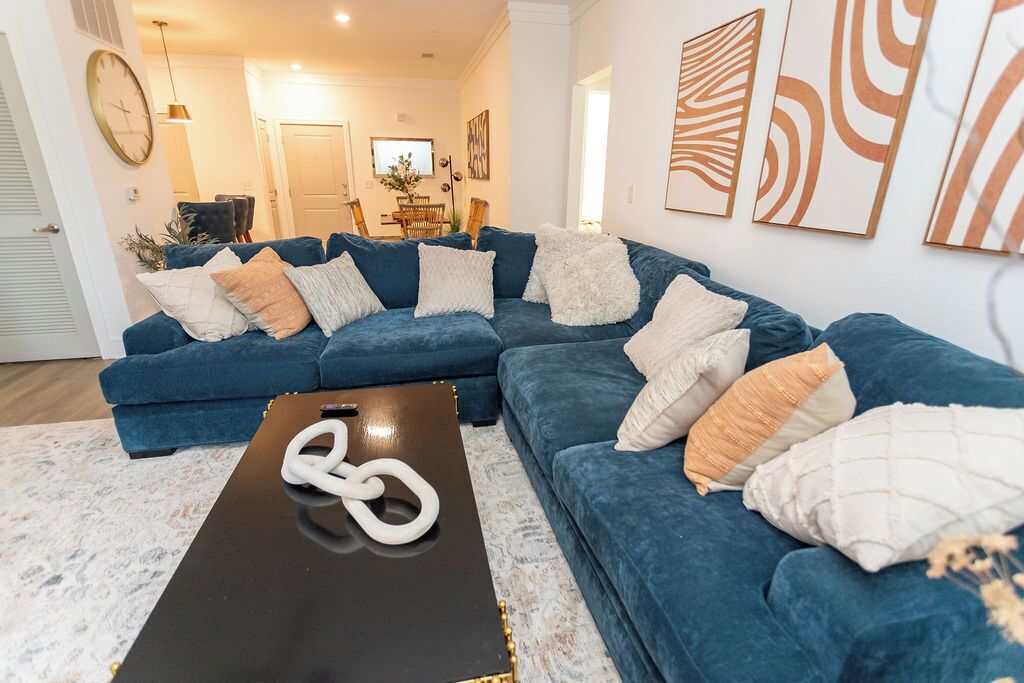 A living room with a sectional sofa, a coffee table, and wall art.