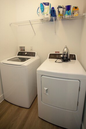 A laundry area with two washing machines and a shelf above containing cleaning supplies. - Lux Master bedroom in a 3 bed 2 bath house (Charlotte)