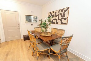 A dining area with a wooden table and wicker chairs, a vase with flowers, and a wall-mounted abstract art piece. - Lux Master bedroom in a 3 bed 2 bath house (Charlotte)