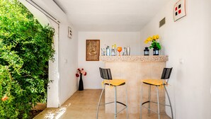 A small, enclosed space with two bar stools, a bar counter, and a framed welcome sign.