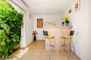 A small, enclosed space with two bar stools, a bar counter, and a framed welcome sign.