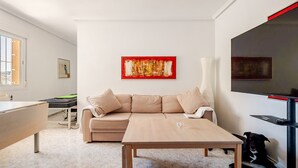 A modern living room with a beige sofa, a wooden coffee table, and a large painting on the wall.