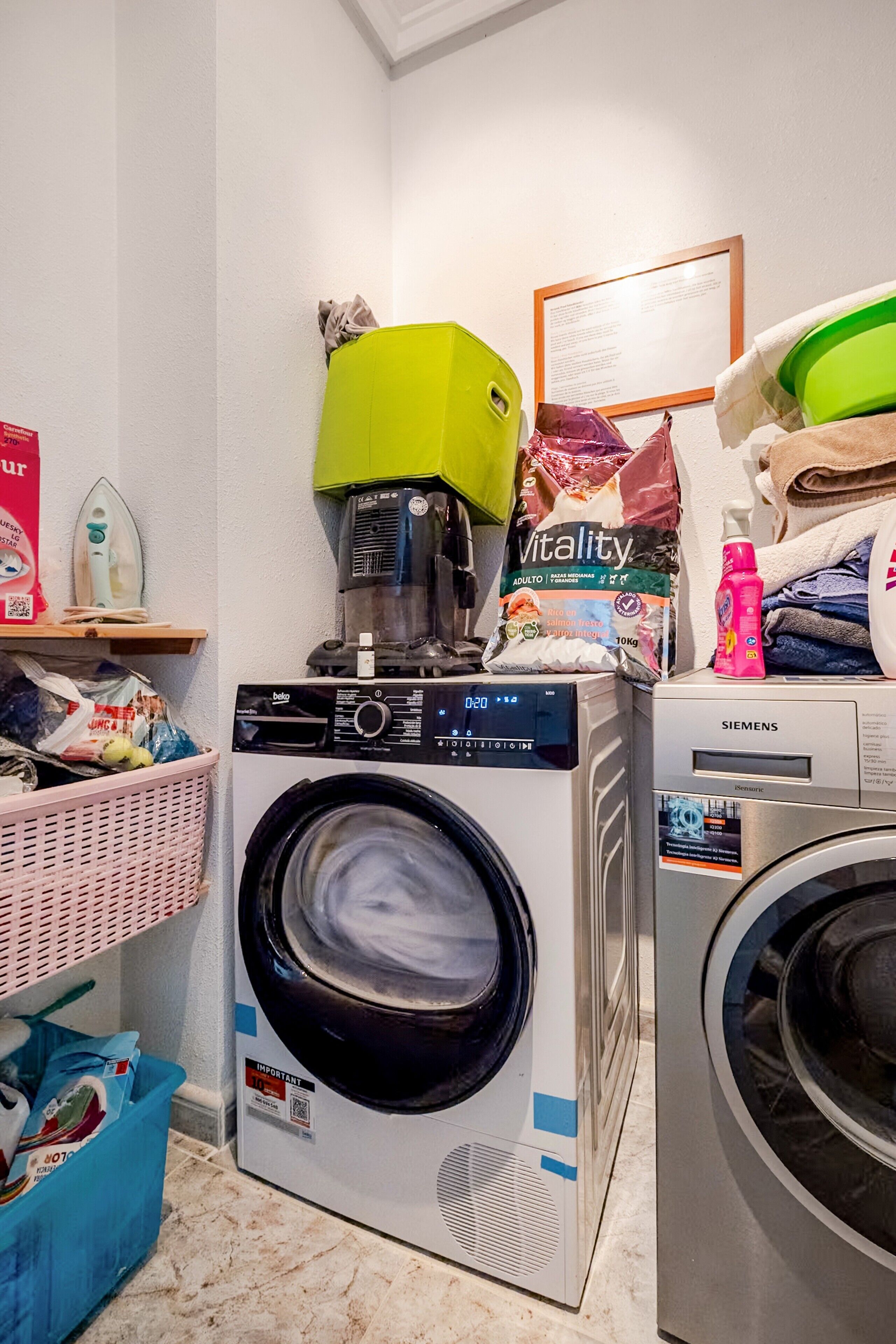 Un espace buanderie comprenant un lave-linge à chargement frontal, un sèche-linge et un appareil combinant lave-linge et sèche-linge.
