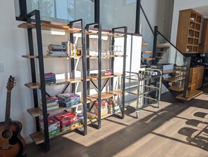 A modern interior with a metal and wooden shelving unit, a staircase, and a kitchen area. - Beautiful Eco-Cottage near Parry Sound (The Archipelago)