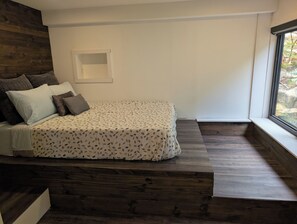 A modern bedroom with a bed, wooden floor, and a window. - Beautiful Eco-Cottage near Parry Sound (The Archipelago)