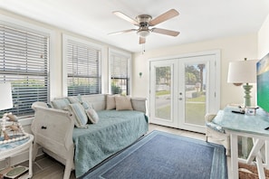 A room with a ceiling fan, a sofa with patterned cushions, a side table with a lamp, and a view through a door with blinds. - Steps to the Private Beach, renovated, 2 Bikes - Time to Coast (Santa Rosa Beach)