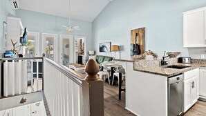 A modern kitchen with white cabinetry, a granite countertop, and a dining area with a table and chairs. - Steps to the Private Beach, renovated, 3 Bikes - Time to Coast (Santa Rosa Beach)