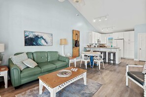 A living room with a green sofa, a coffee table, and a painting on the wall. - Steps to the Private Beach, renovated, 2 Bikes - Time to Coast (Santa Rosa Beach)