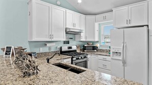 A kitchen with white cabinets, a granite countertop, a stove, a microwave, and a refrigerator. - Steps to the Private Beach, renovated, 3 Bikes - Time to Coast (Santa Rosa Beach)