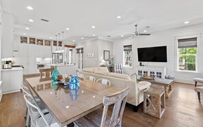 A spacious living area with a dining table, sofa, and TV. - Pirate's Smile (Panama City Beach)