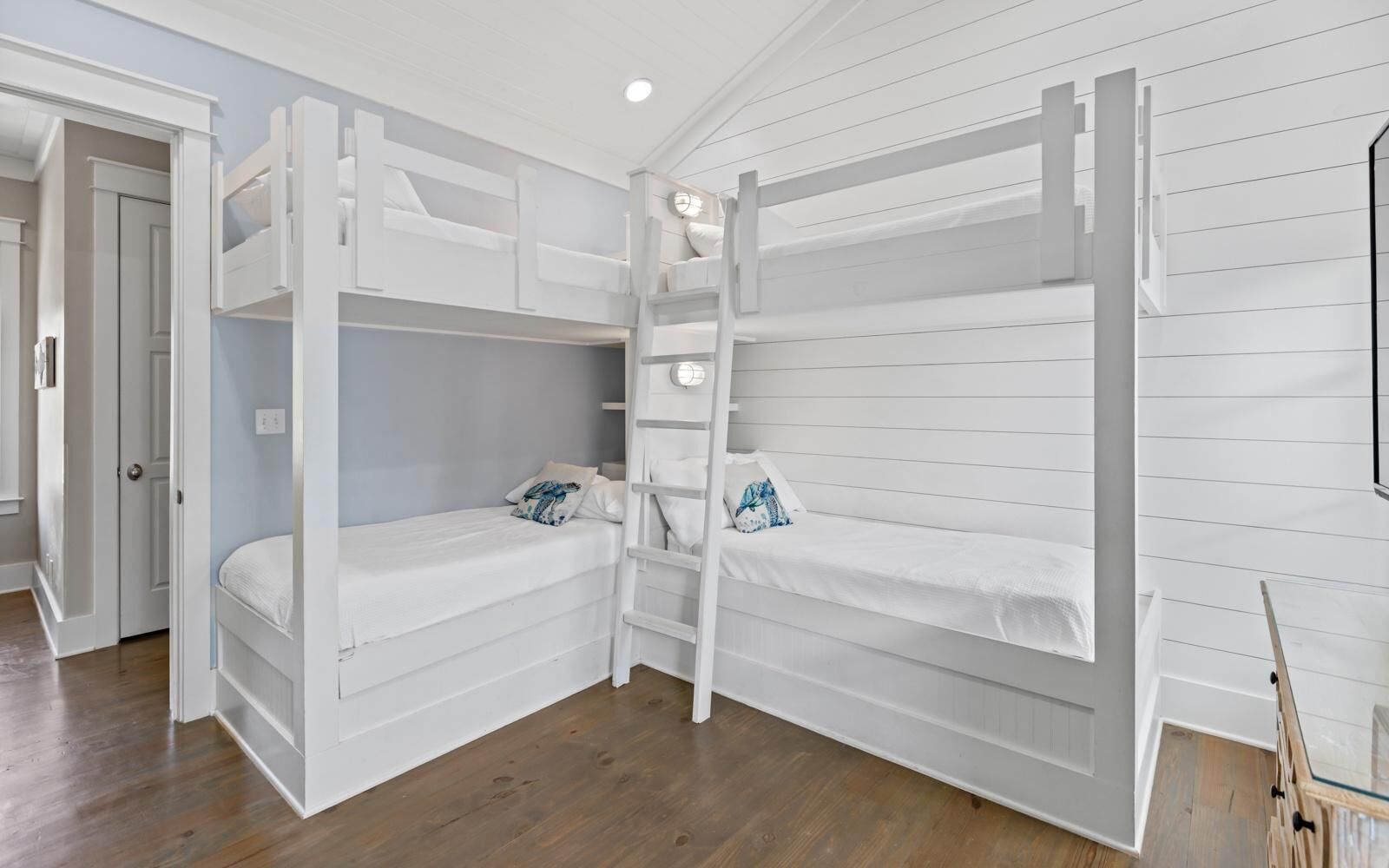 A room with bunk beds, a ladder, and a door leading to another room.