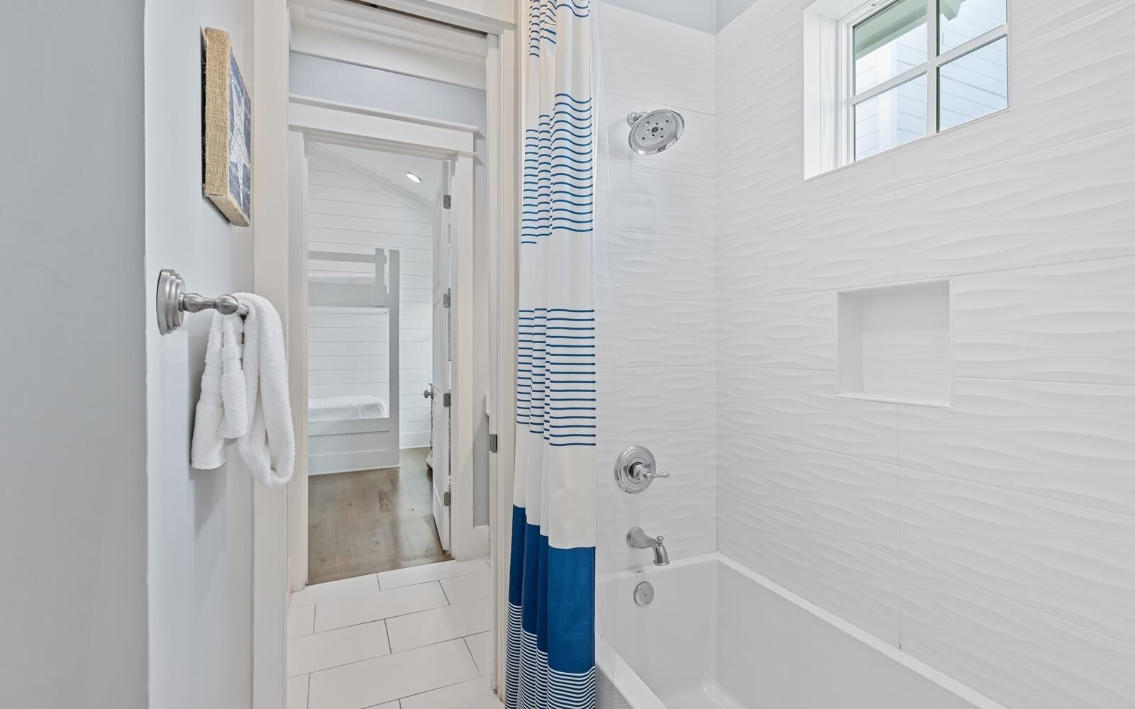 A bathroom with a shower, a bathtub, and a door leading to another room.