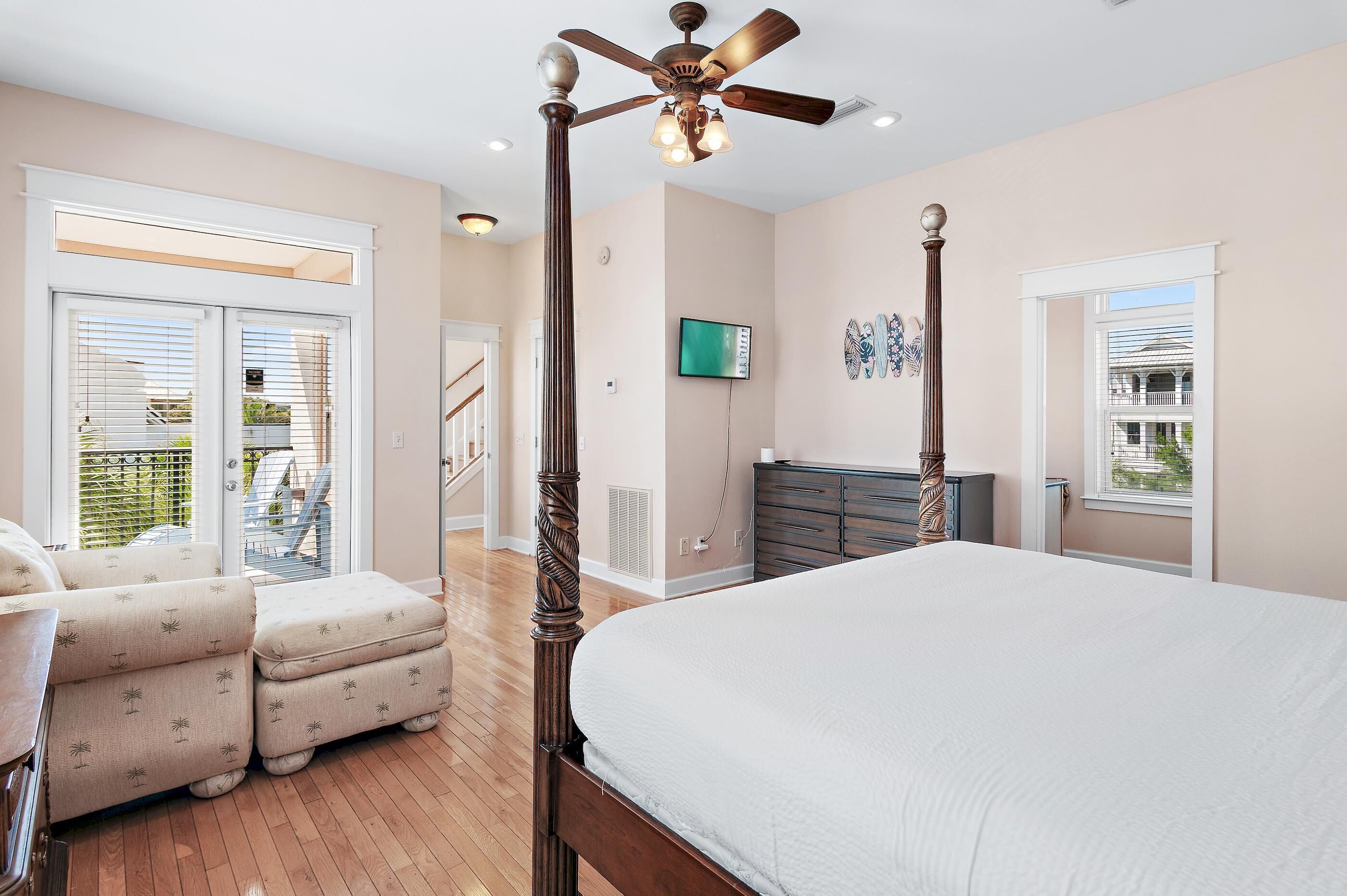 A bedroom with a large bed, a ceiling fan, and a view of the outdoors through a window.