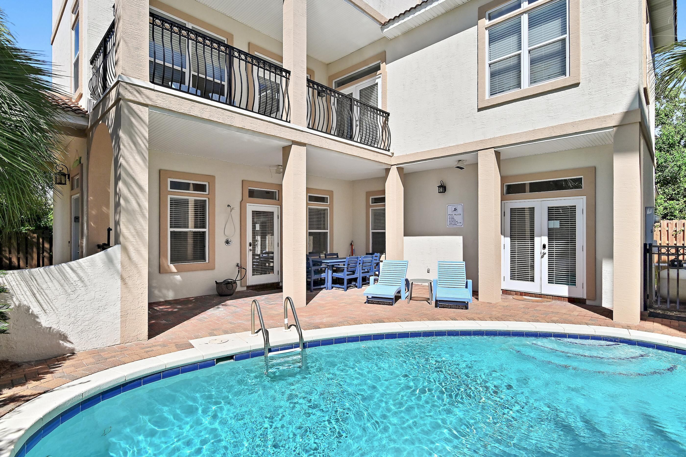 A two-story building with a swimming pool, outdoor seating, and a sign indicating pool rules.